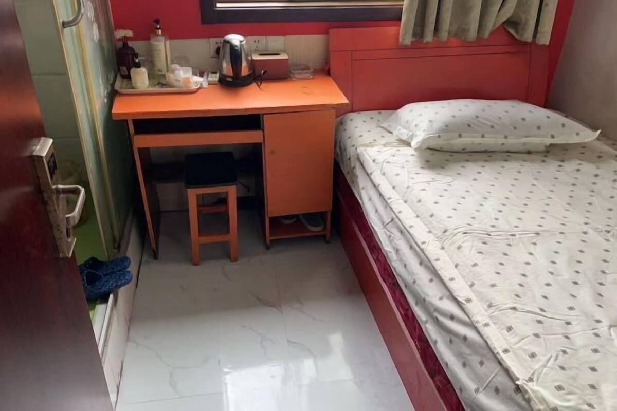 A compact room with a bed, a small desk, and a chair.