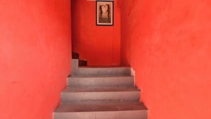 Uma escadaria com paredes vermelhas e um quadro pendurado na parede superior.