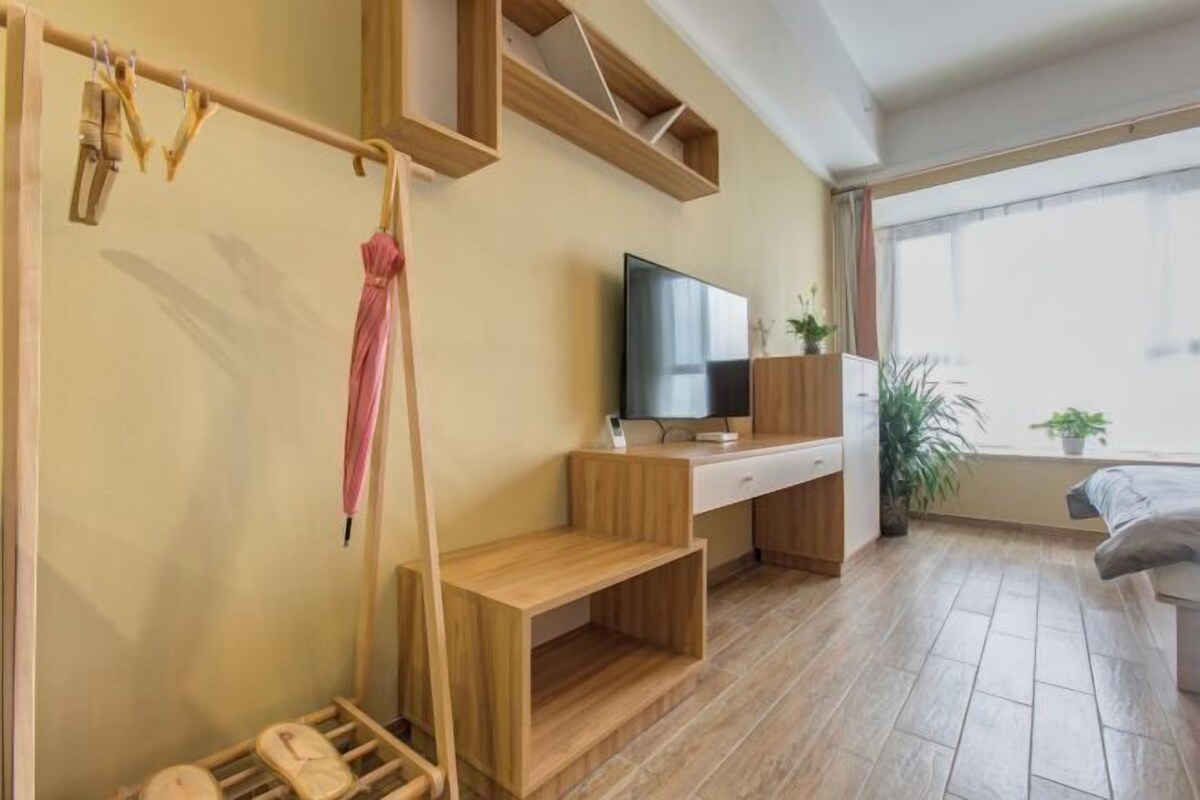 A modern room with a wooden desk, a television, a bed, and a window with a view.