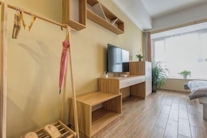 Ett modernt rum med ett skrivbord i trä, en tv, en säng och ett fönster med utsikt.