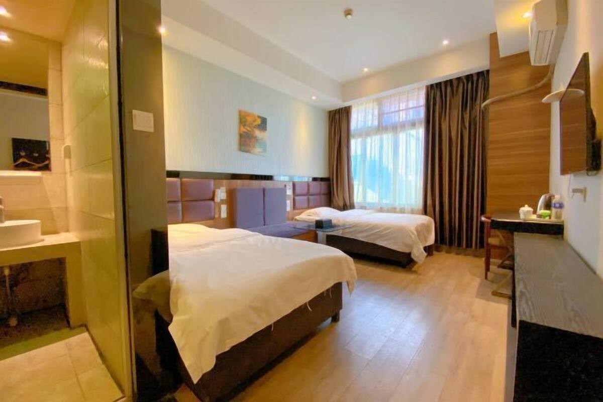 A hotel room with two beds, a bathroom, and a small kitchenette.