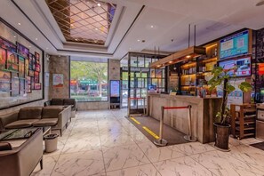 A hotel lobby with seating, a reception desk, and a large window. - Gujia Hotel (Xinxiang)