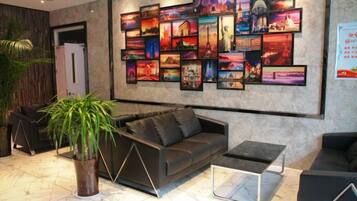 A modern lobby with a black leather sofa, a coffee table, and a large wall of framed pictures.