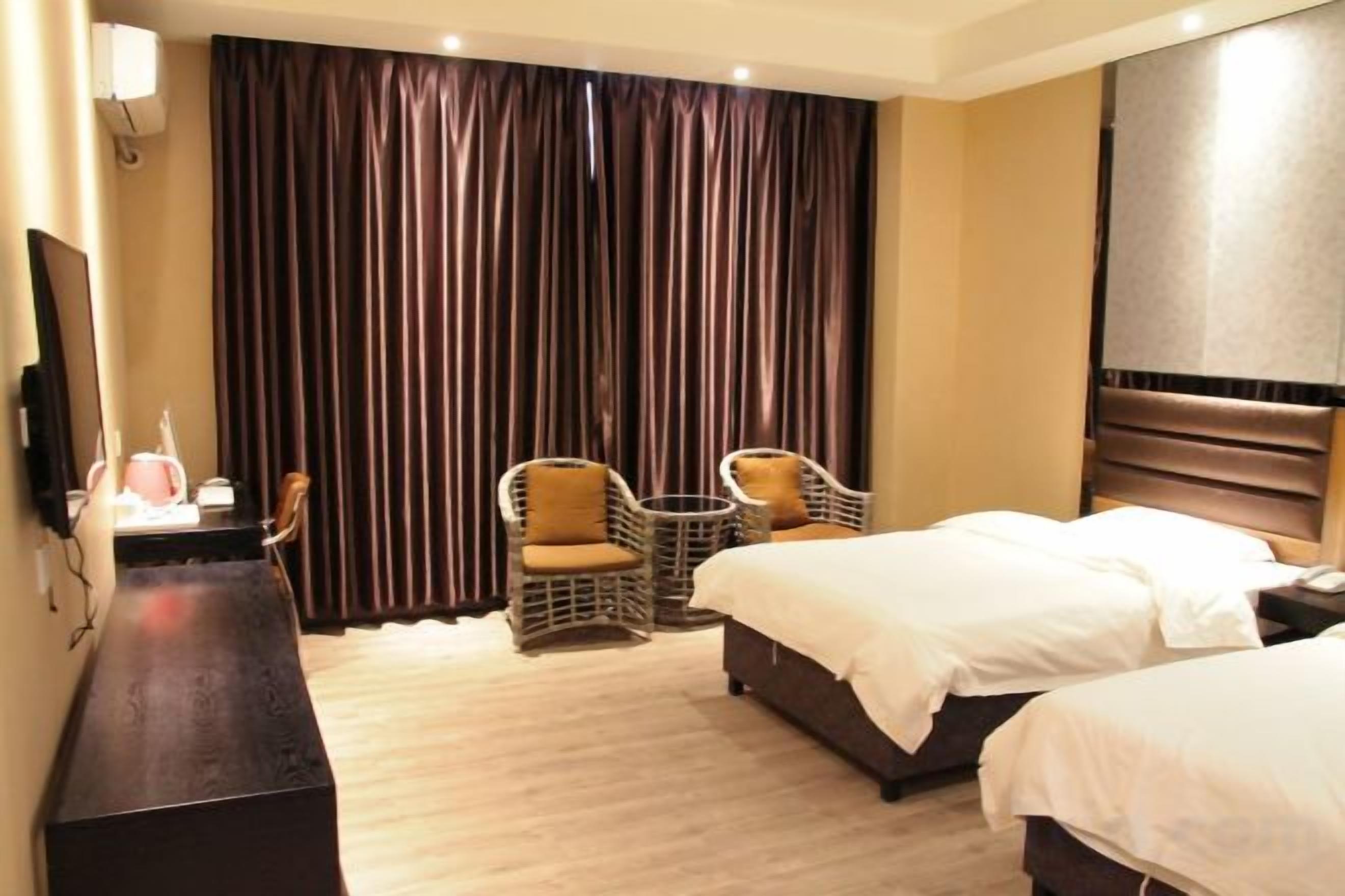 A hotel room with two beds, a desk with a chair, and a small table with two chairs.