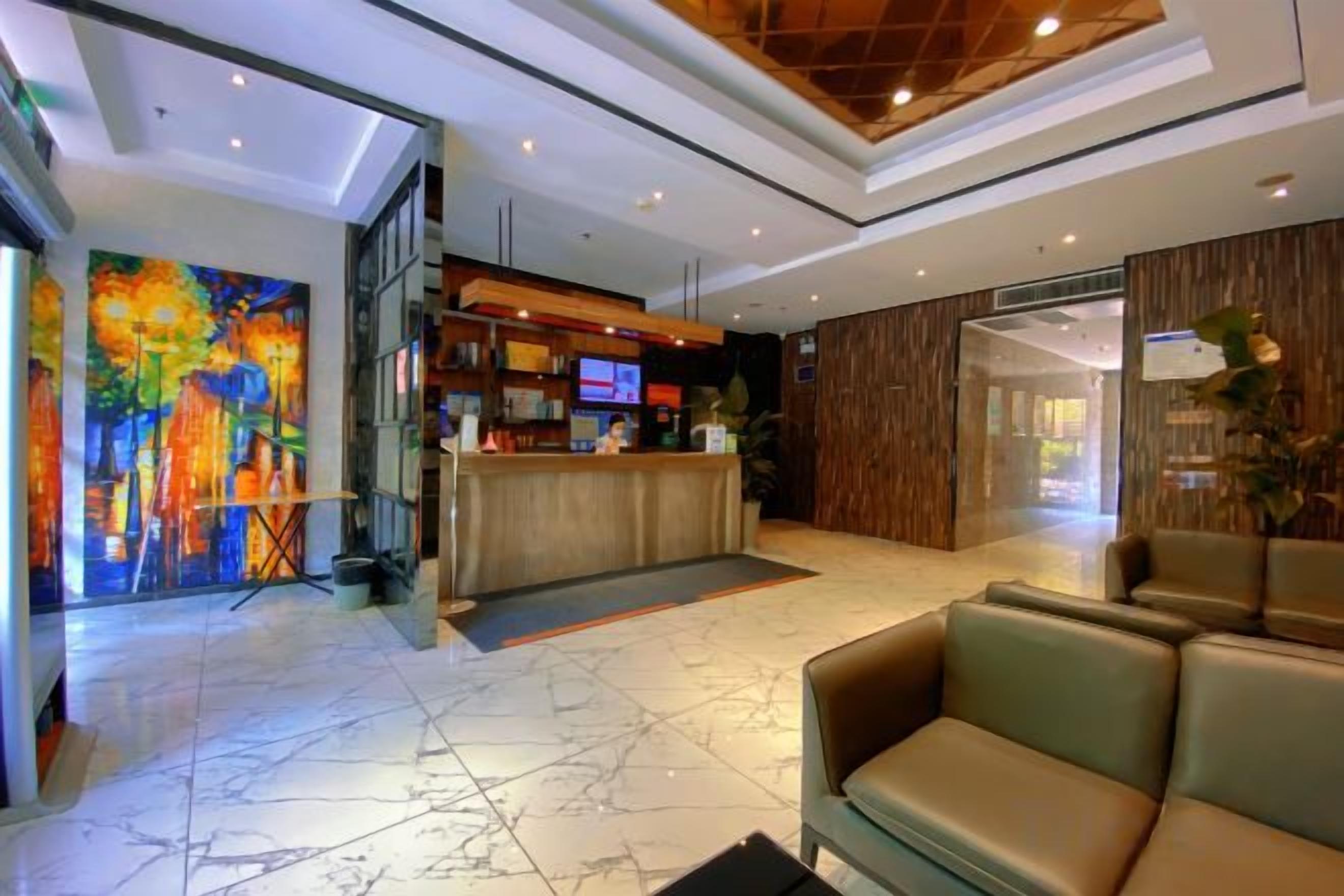 A hotel lobby with a reception desk, seating area, and a large abstract painting.