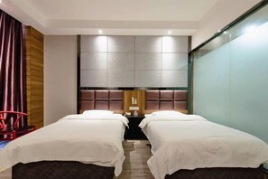 A hotel room with two beds, a wooden headboard, a small table, and a red chair. - Gujia Hotel (Xinxiang)