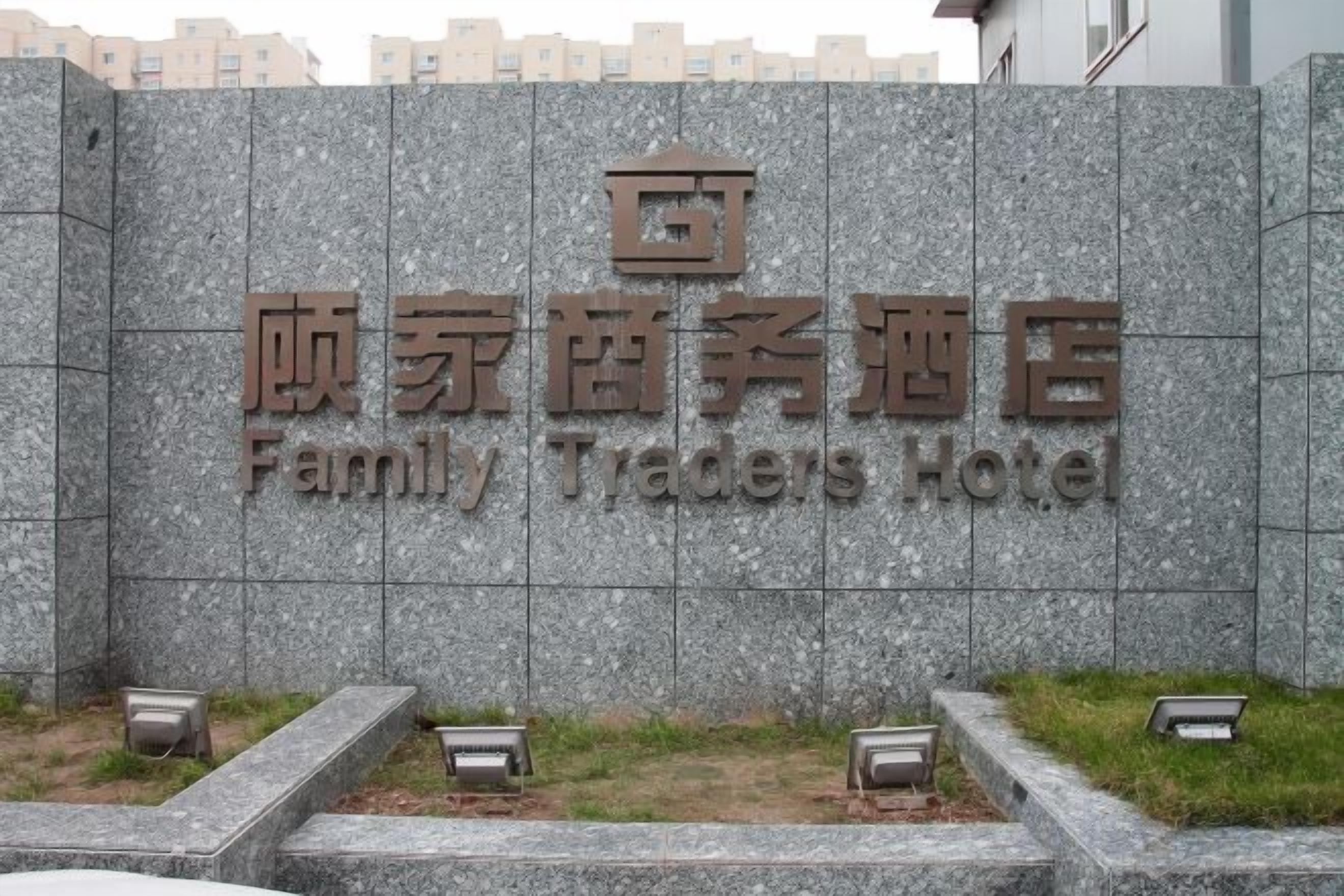 Una pared de piedra con la inscripción 'Family Traders Hotel' escrita en chino e inglés.
