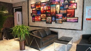 A modern lobby with a black sofa, a coffee table, and a large wall art display. - Gujia Hotel (Xinxiang)