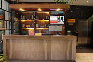 A reception desk with a wooden finish, a digital display, and a small plant.