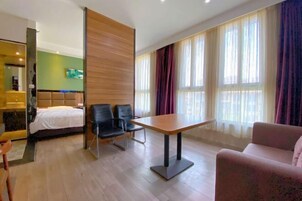Una habitación de hotel con cama, escritorio, dos sillas y sofá.