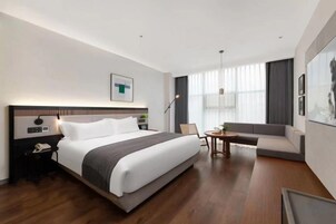 Una habitación de hotel moderna con una cama grande, un sofá, un escritorio y una silla.