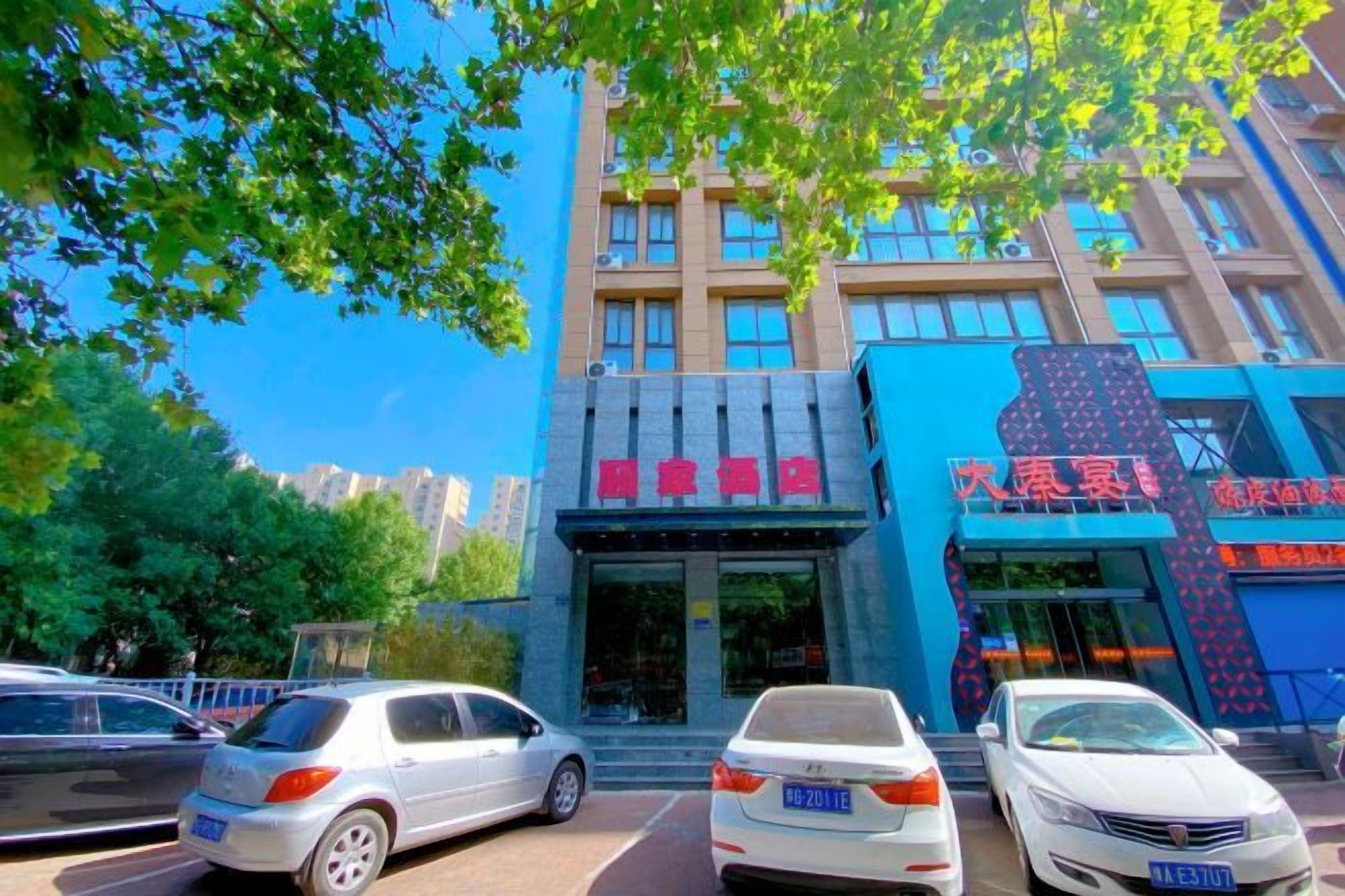 A multi-story building with a blue facade and a red sign. There are cars parked in front.