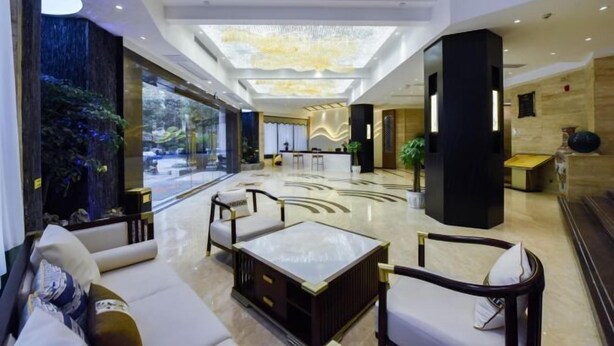 A spacious lobby with a reception desk, seating area, and a large window overlooking a garden. - Chongqing Jinchuan Hotel (Chongqing)