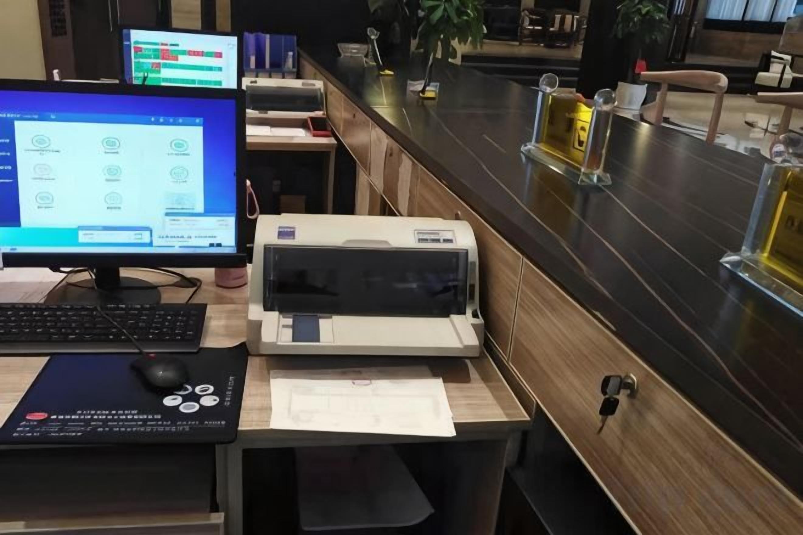 A reception desk with a computer monitor, printer, and a desk with a keyboard and mouse.