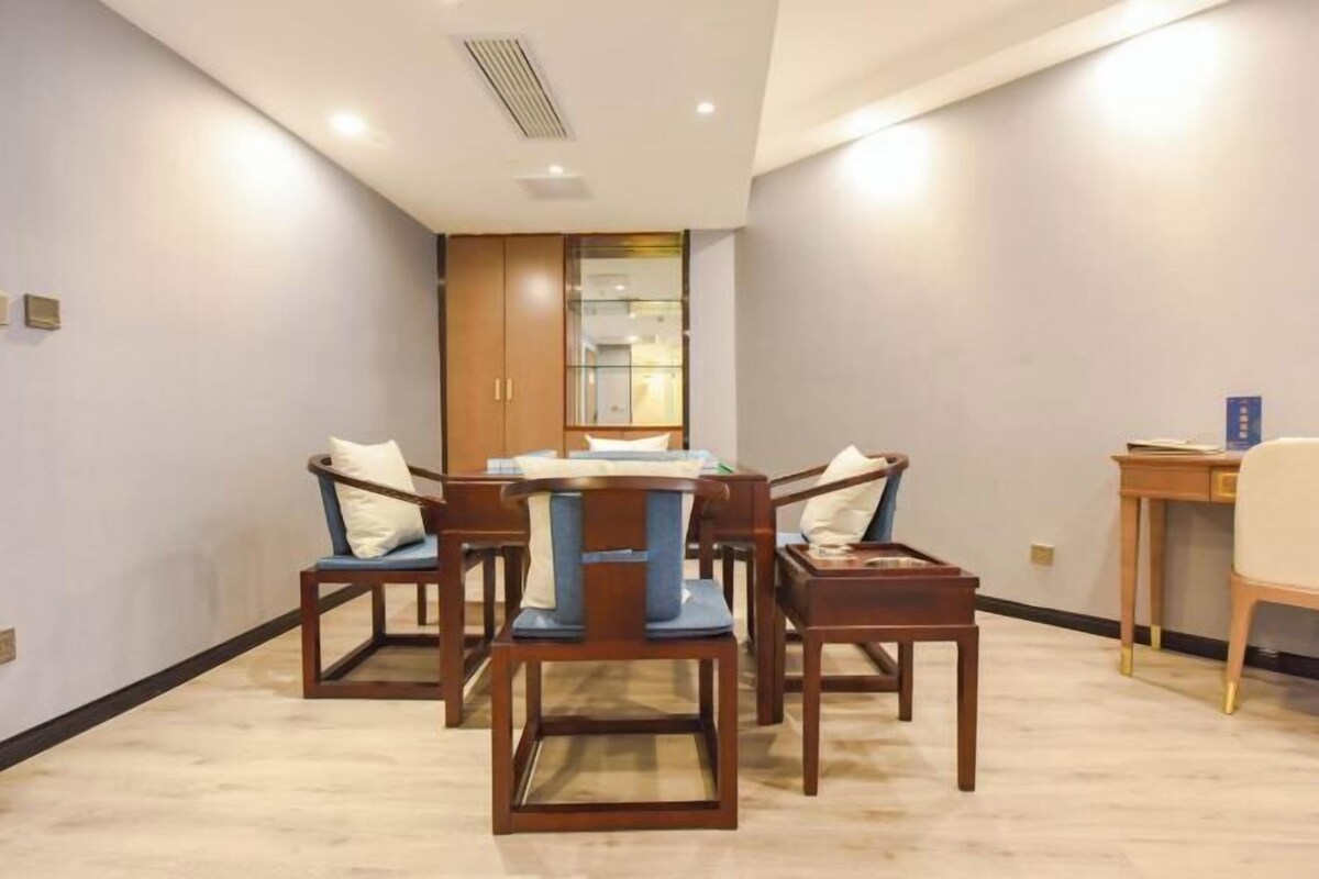 A modern dining area with a round table and six wooden chairs, each with a cushion.