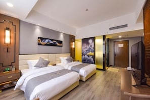 Une chambre d’hôtel avec deux lits, un bureau et une télévision.
