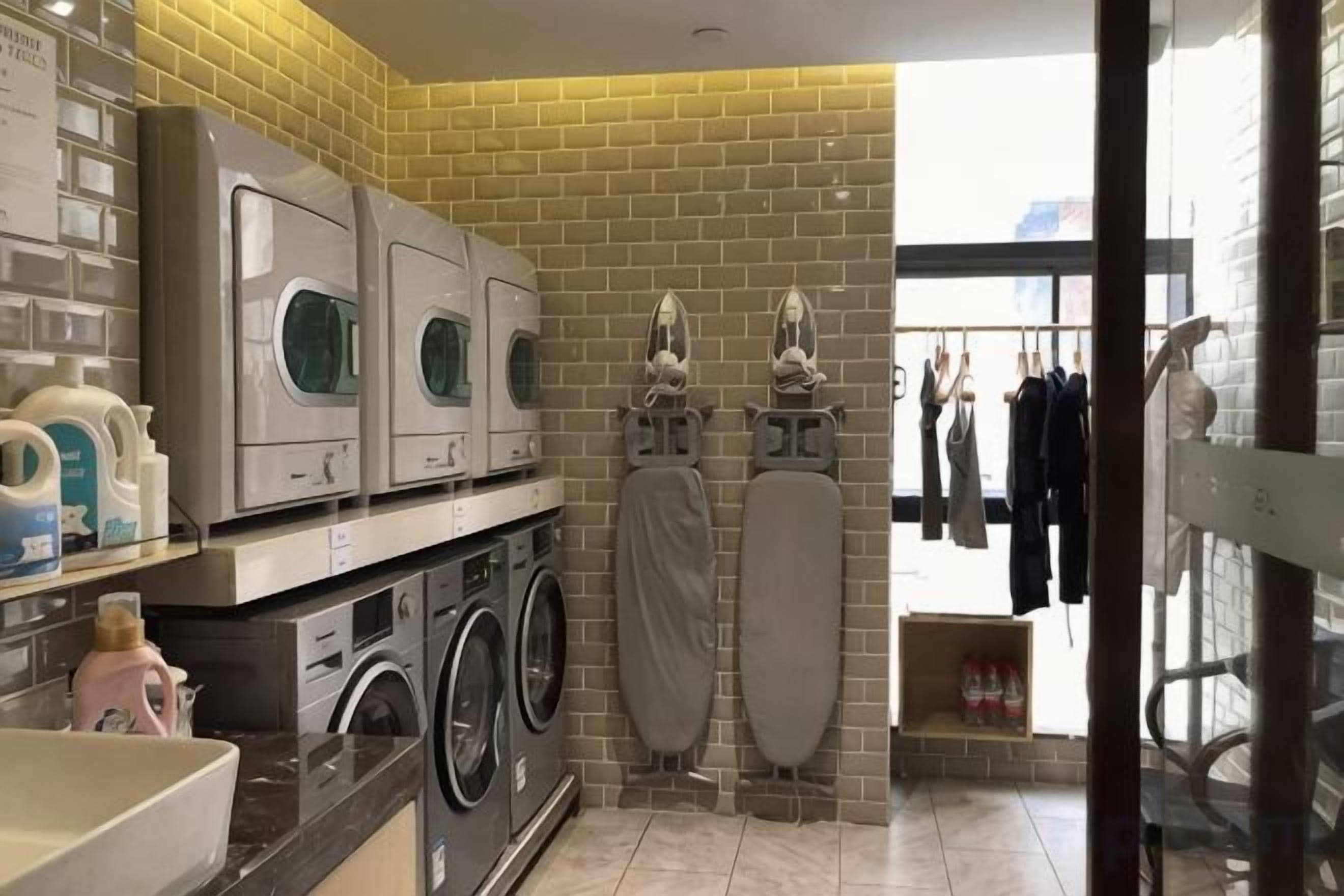 Une buanderie équipée de plusieurs machines à laver, d’un étendoir et d’un portant à vêtements.