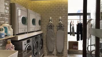Une buanderie équipée de plusieurs machines à laver, d’un étendoir et d’un portant à vêtements.