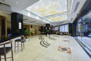 Un vestíbulo de hotel con mostrador de recepción, zona de estar y grandes ventanales.