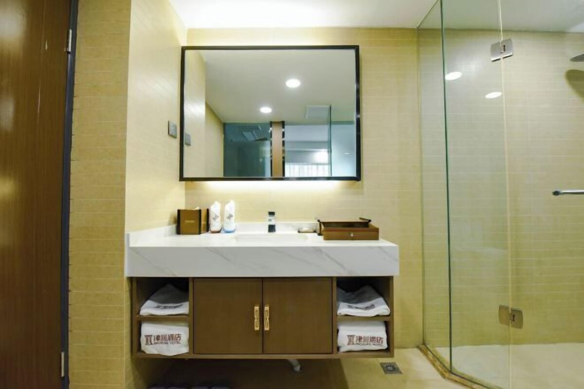 A bathroom with a mirror, sink, and glass shower enclosure.