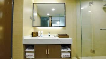 A bathroom with a mirror, sink, and glass shower enclosure.