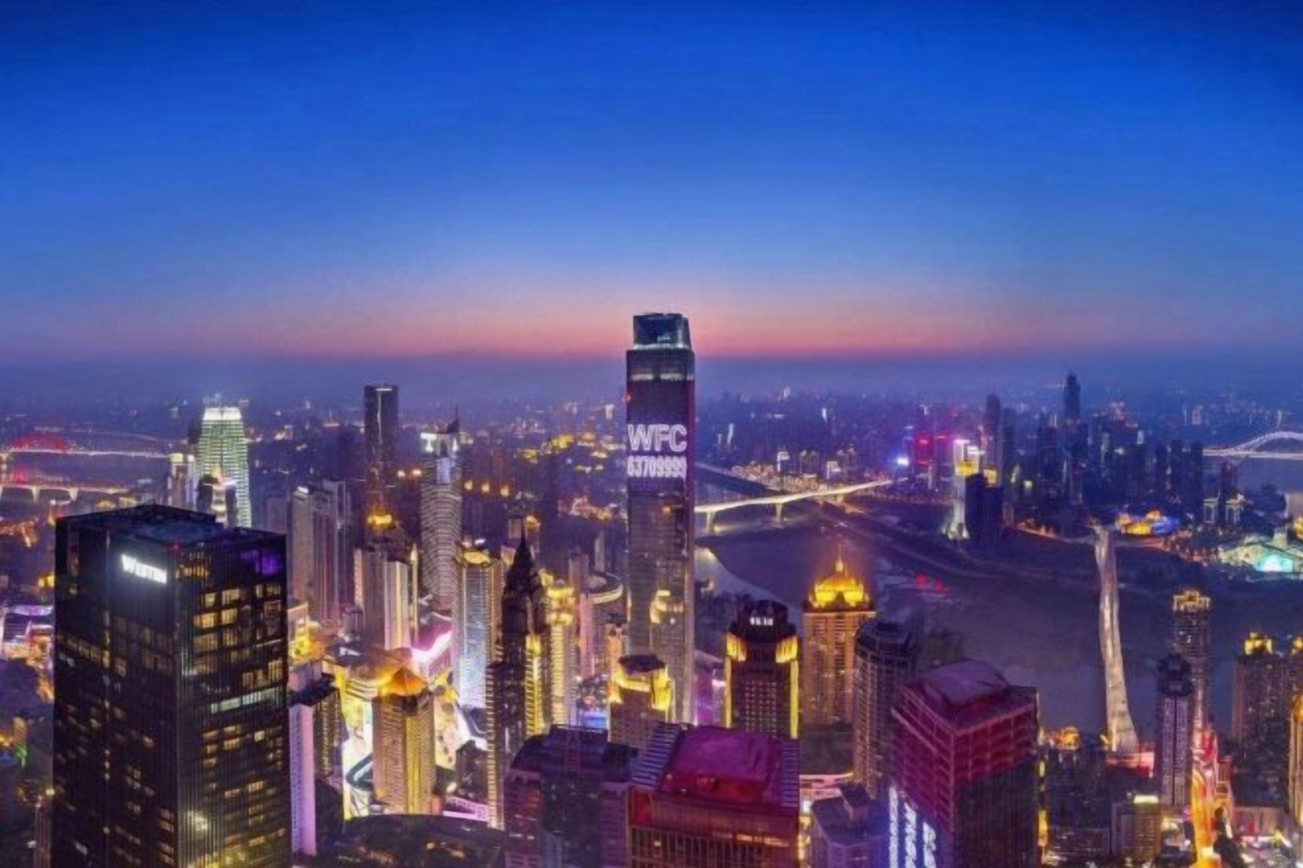 A cityscape at twilight with illuminated skyscrapers and a river.