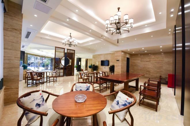 A modern dining area with multiple tables and chairs, a chandelier, and a television mounted on the wall.