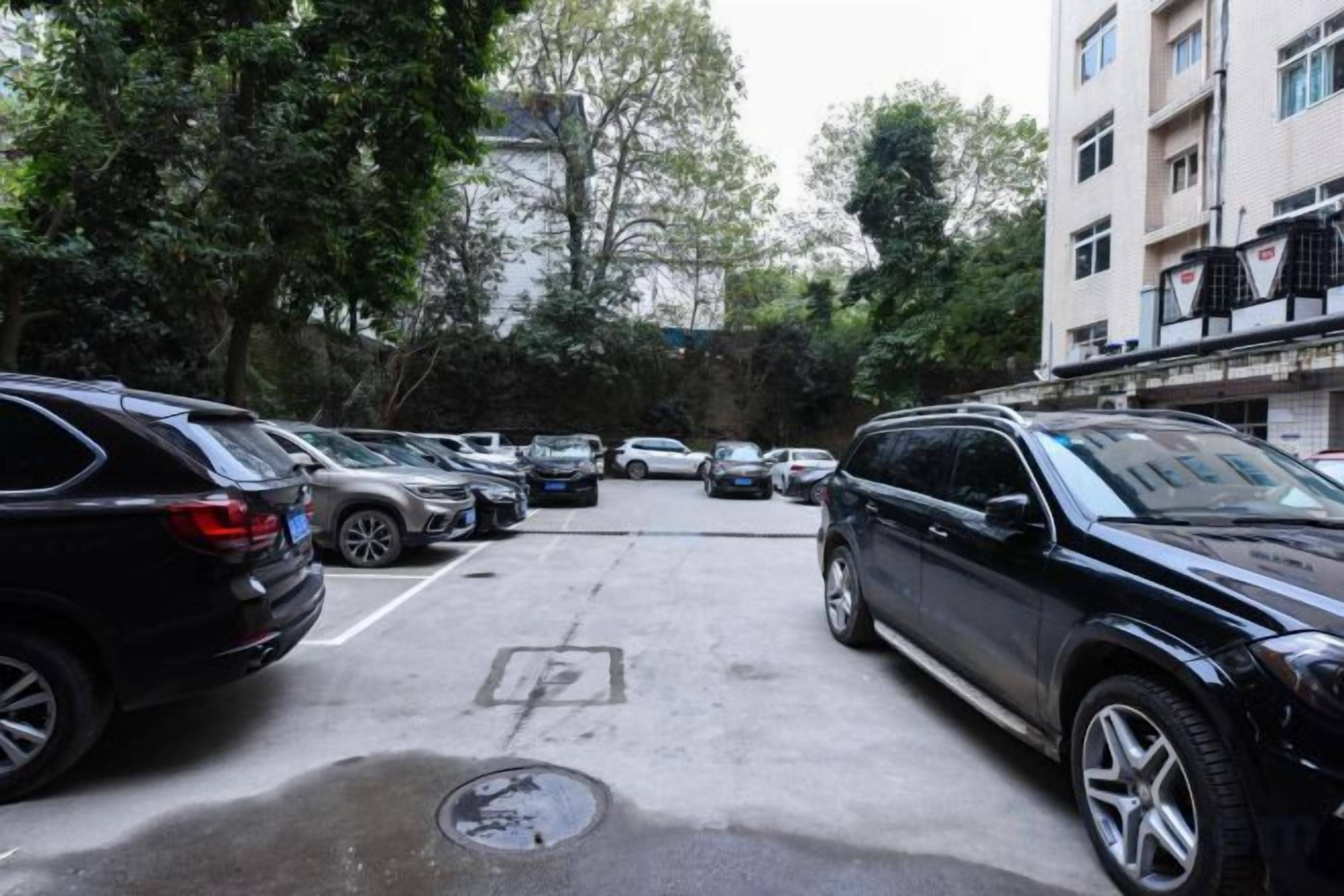 A parking lot with multiple cars and a building in the background.