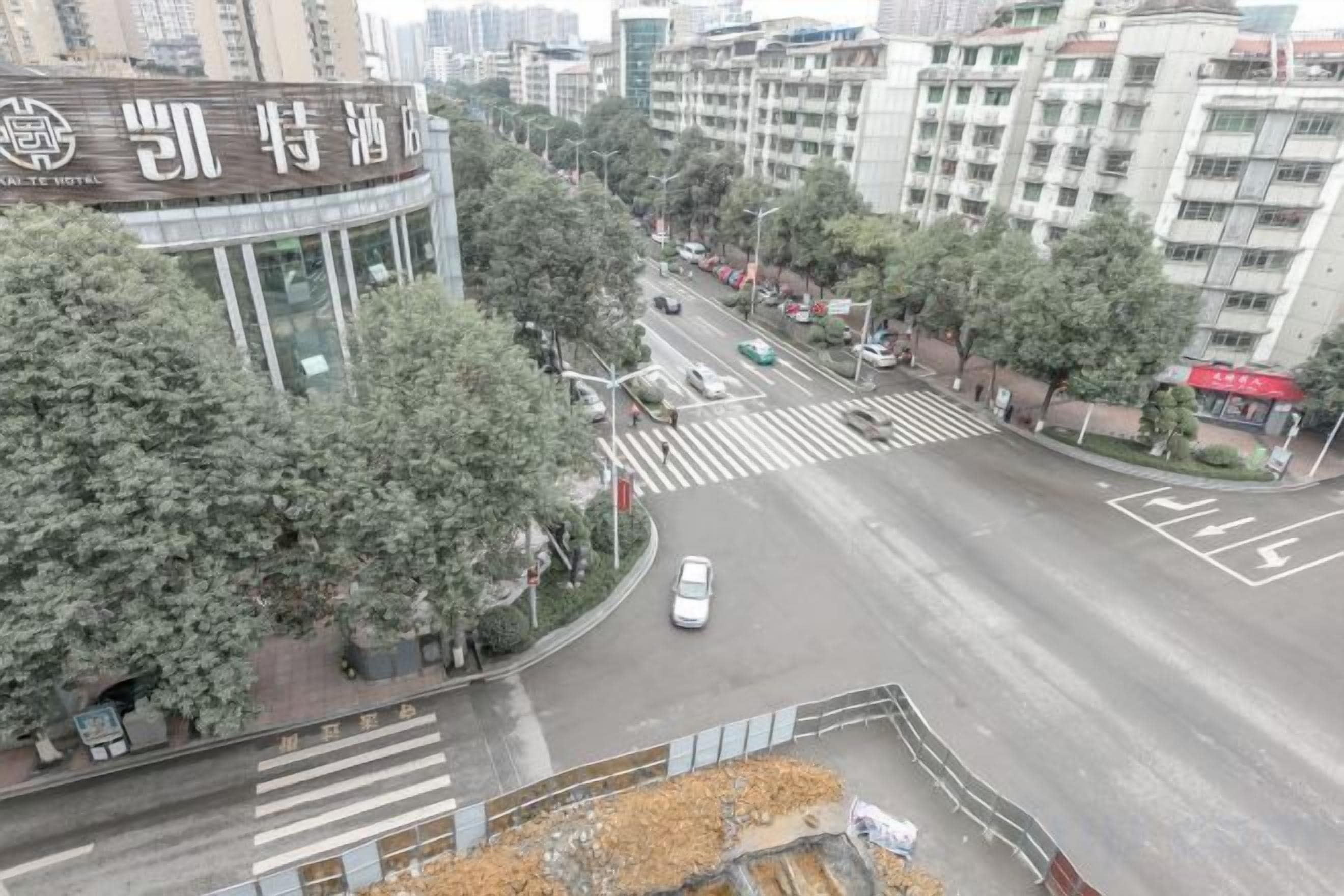 A hotel with a prominent sign, a crosswalk, and a road with vehicles.
