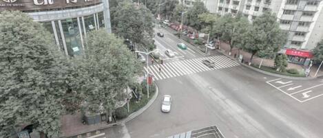 A hotel with a prominent sign, a crosswalk, and a road with vehicles.
