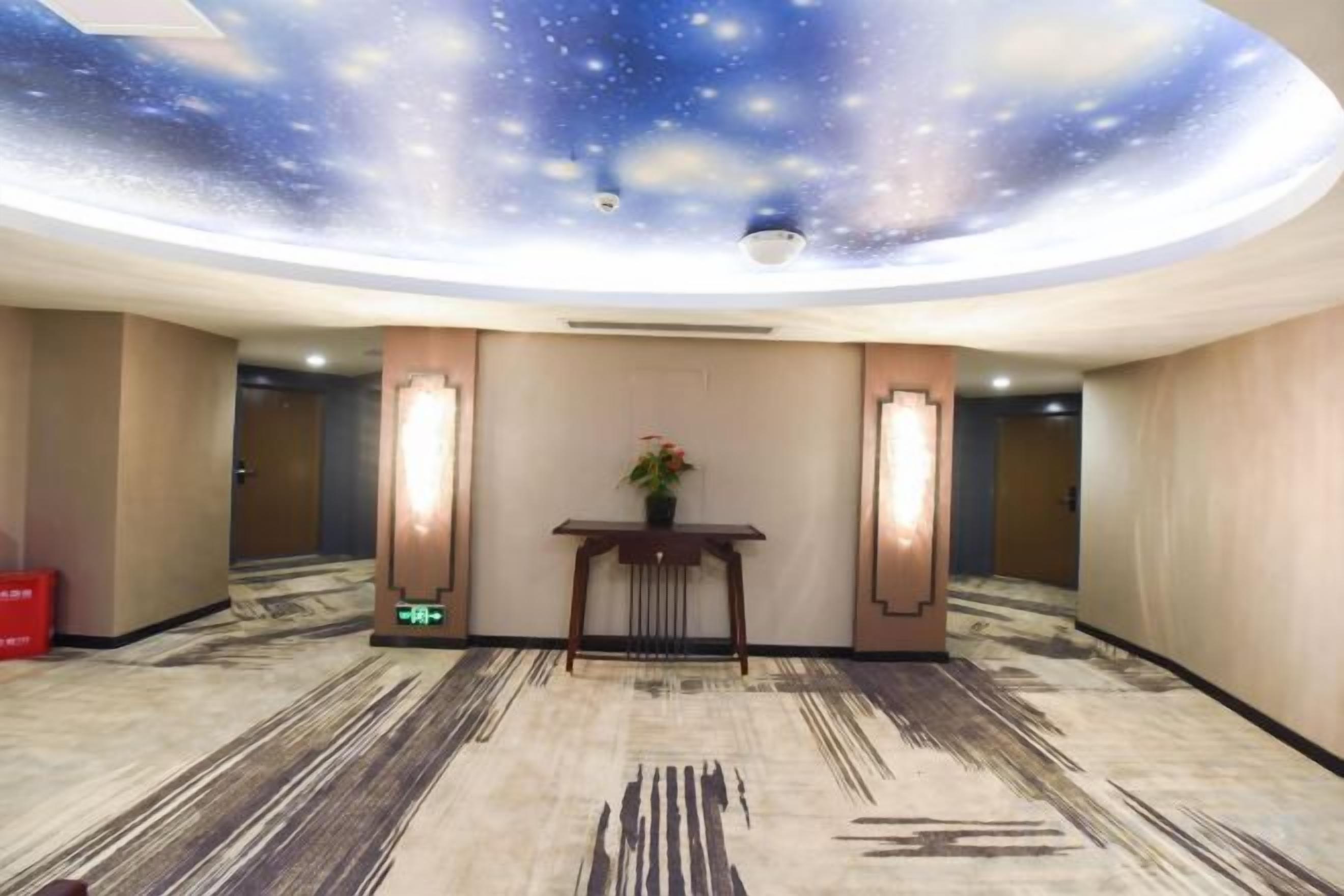 A hotel lobby with a starry ceiling, a reception desk, and a carpeted floor.