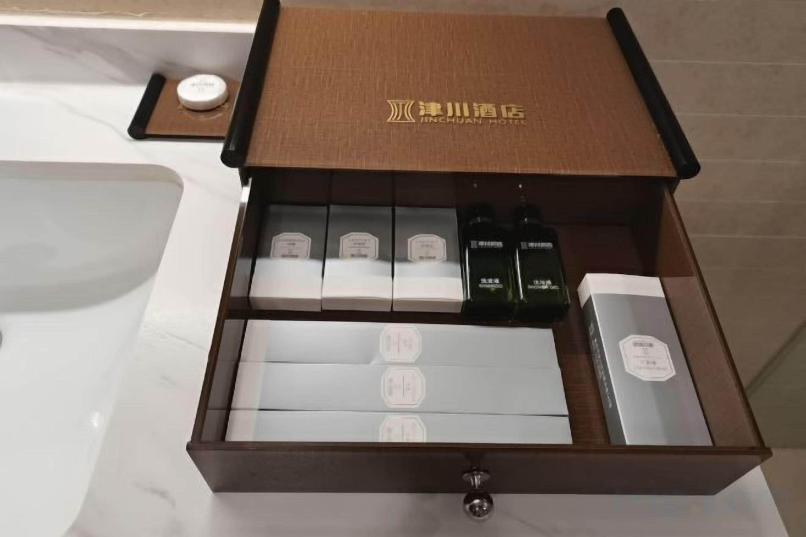 A drawer with toiletries and a brown box with hotel branding.