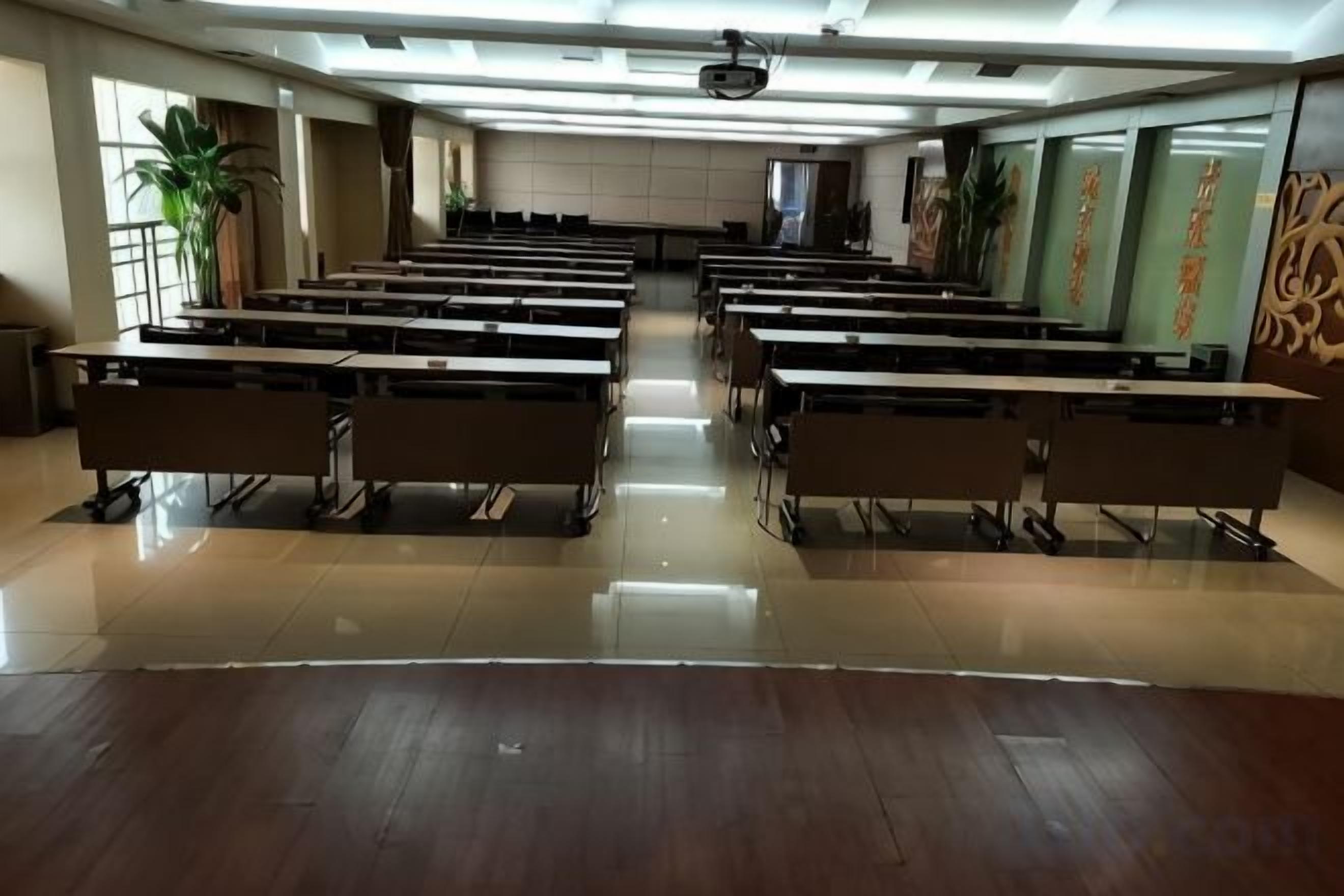 A classroom with rows of desks and chairs, a projector at the front, and a large window on the left.