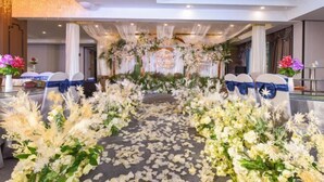 An indoor venue with a floral aisle leading to a stage, white chairs with blue sashes, and a chandelier. - Chongqing Jinchuan Hotel (Chongqing)