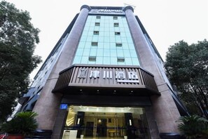 Un edificio alto dal design moderno, con un ingresso ben visibile caratterizzato da porte in vetro e un cartello sopra.