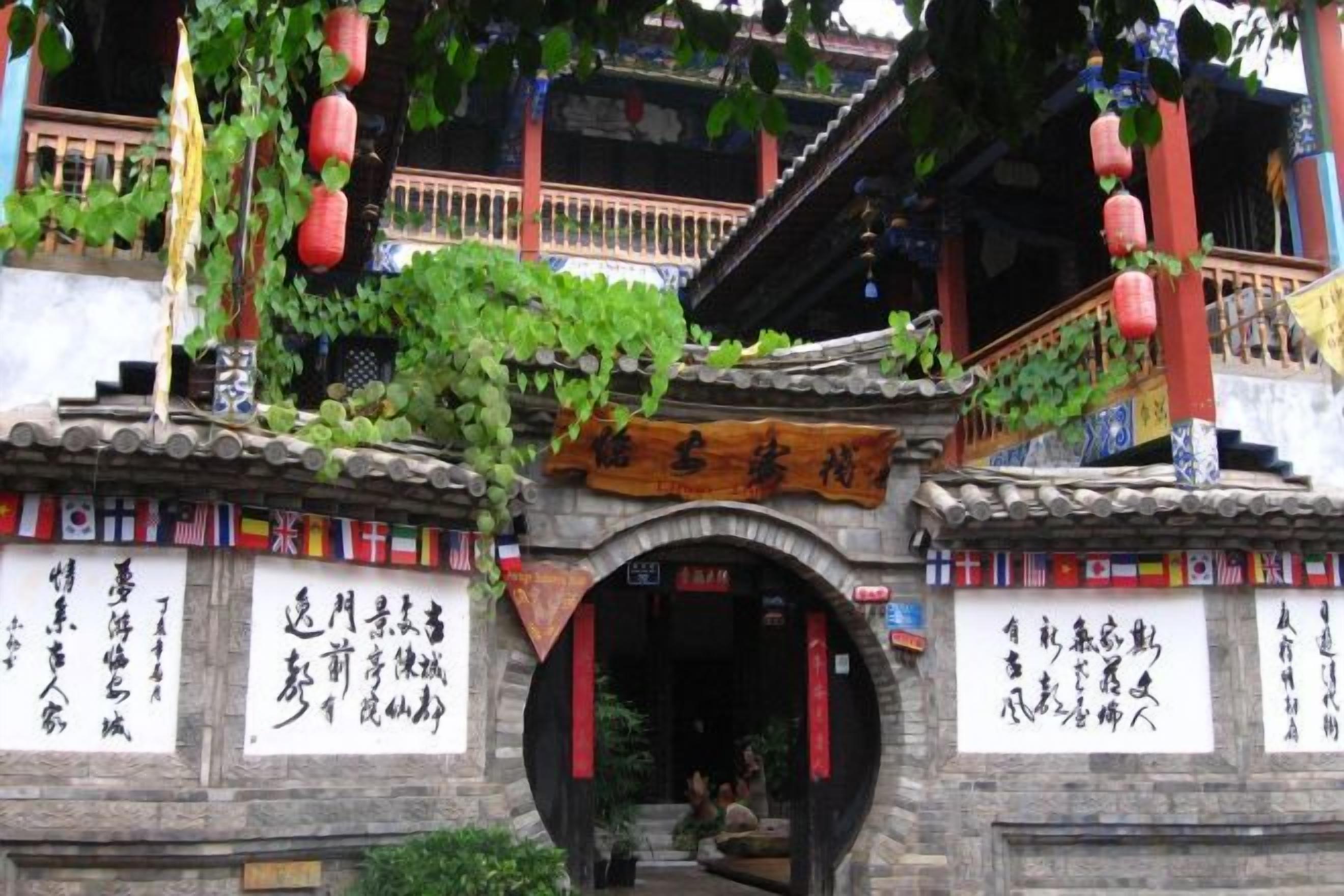 A traditional Chinese gate with inscriptions, a staircase, and hanging lanterns.