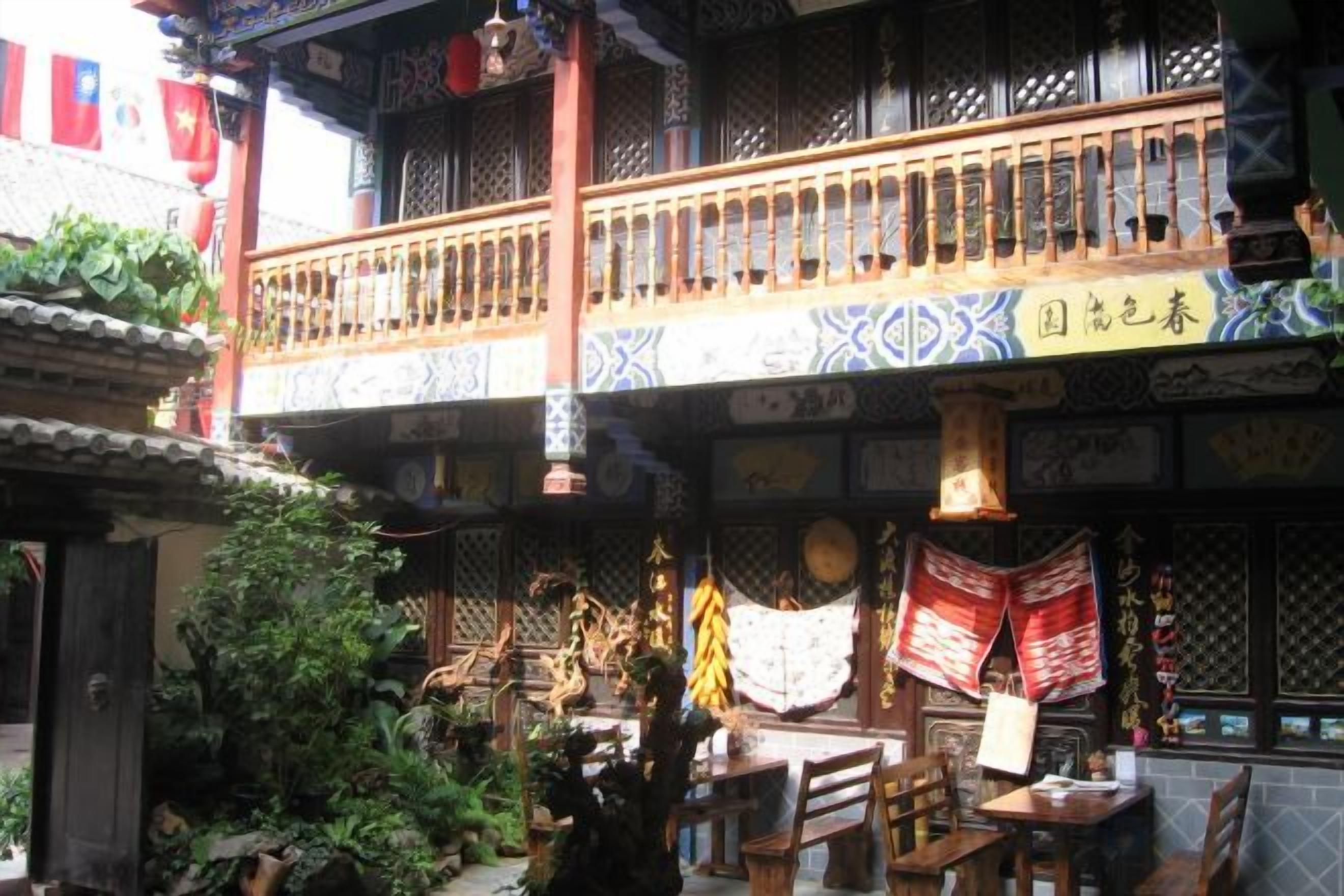 Ein traditioneller chinesischer Innenhof mit einem hölzernen Balkon, hängenden Verzierungen und einem Essbereich.