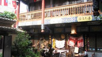 Ein traditioneller chinesischer Innenhof mit einem hölzernen Balkon, hängenden Verzierungen und einem Essbereich.