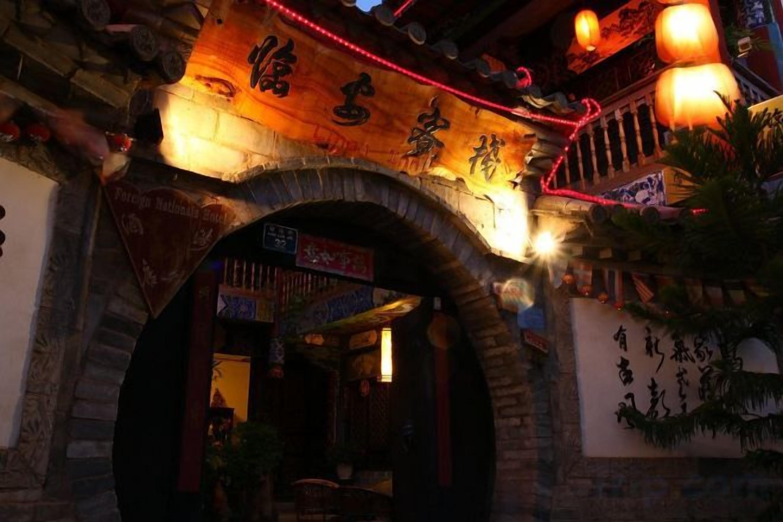 Una entrada arqueada con caracteres chinos tradicionales y un cartel encima.