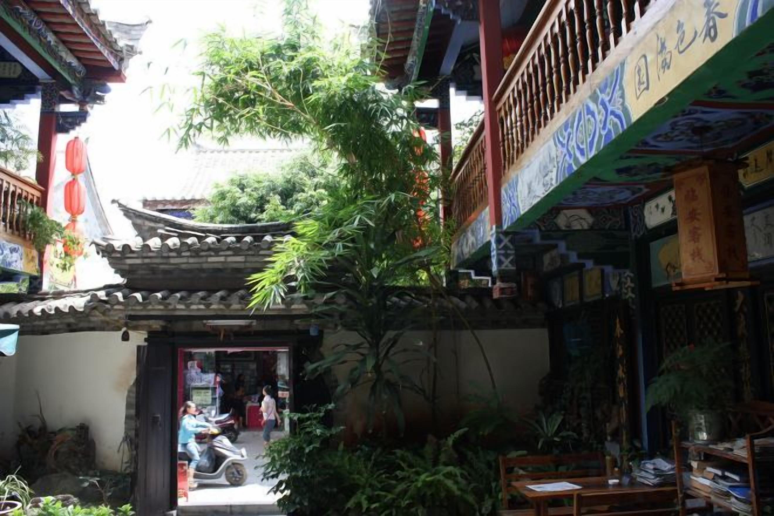 A traditional courtyard with a tiled roof, potted plants, and a wooden door.