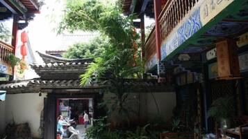 A traditional courtyard with a tiled roof, potted plants, and a wooden door.
