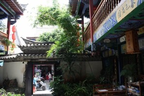 A traditional courtyard with a tiled roof, potted plants, and a wooden door.