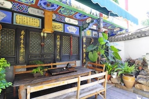 A traditional Chinese building with a wooden bench and potted plants. - Lin An Inn (Jianshui)
