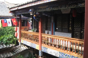 A traditional building with a tiled roof, a balcony with a wooden railing, and a door with intricate patterns. - Lin An Inn (Jianshui)