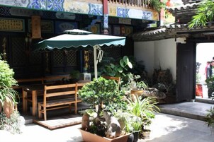 Un patio tradicional con un banco de madera, plantas en macetas y un techo de tejas.