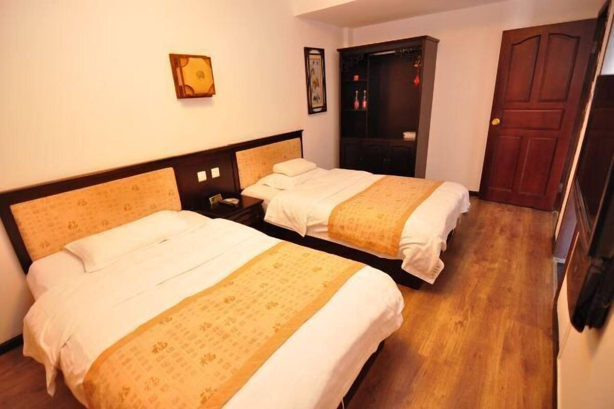 Une chambre d’hôtel avec deux lits, une armoire, une porte et un mur orné d’un tableau encadré.