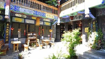A traditional courtyard with wooden furniture, potted plants, and decorative elements.