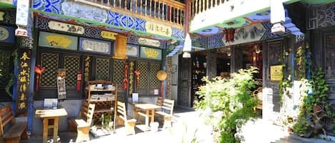 A traditional courtyard with wooden furniture, potted plants, and decorative elements.
