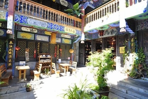 Un patio tradicional con mobiliario de madera, plantas en macetas y elementos decorativos.