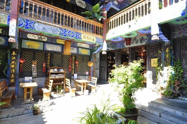 A traditional courtyard with wooden furniture, potted plants, and decorative elements.